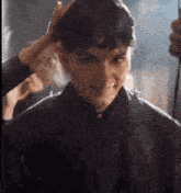 a man is getting his hair cut by a woman in a black jacket .
