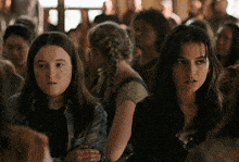 two girls are sitting in a crowd and one has a braided hairdo