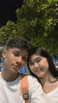 a man and a woman posing for a picture with trees in the background
