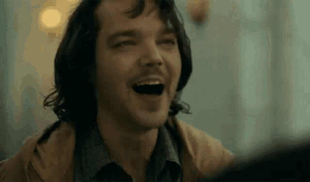 a close up of a man laughing with his mouth open in a room .