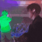 a man in a green hoodie stands in front of a crowd at a concert