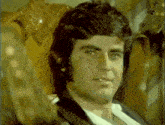 a man with long hair is sitting in a chair
