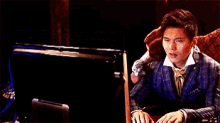 a man in a suit is sitting in front of a piano and using a computer