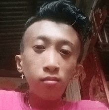 a young man with a cross in his ear looks at the camera