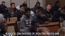 a group of men are sitting at tables in a classroom with the words `` knock on wood if you 're with me ''