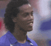 a man with curly hair wearing a blue shirt is smiling