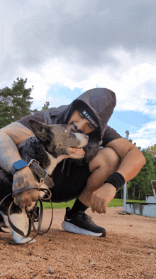 a man kneeling down with a dog wearing a hoodie that says ' freestyle '