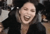 a woman is laughing with her mouth open while wearing a black hat .