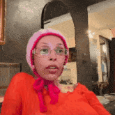 a woman wearing glasses and a pink hat with a bow around her neck