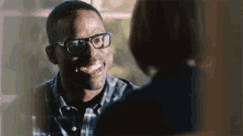 a man with glasses is smiling at a woman .