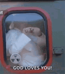 a man is looking out of a window with the words `` god loves you '' .