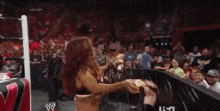 a woman in a wrestling ring with a w logo on the wall behind her