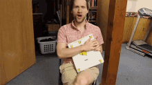 a man in a red shirt holds a white box with pikachu on it
