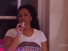 a woman wearing a t-shirt that says ' zeuse ' on it is eating something