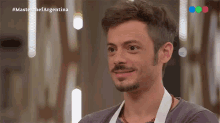 a man with a mustache is smiling in front of a screen that says masterchef argentina