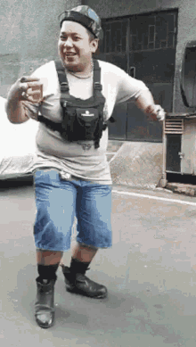 a man in a white shirt and blue shorts is standing on a street .