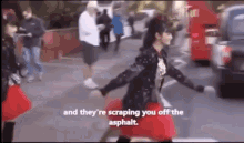 a woman in a red skirt is walking down the street and they 're scrapping you off the asphalt .