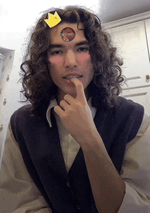 a young man with long curly hair has a sticker on his forehead that says ' king '