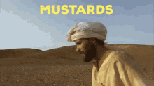 a man in a white turban stands in a desert with the word mustards behind him