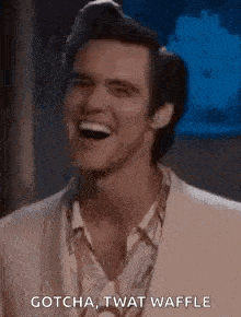 a man in a suit is laughing and saying `` gotcha twat waffle '' .