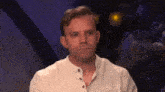 a man in a white shirt is sitting in front of a purple background .