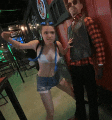 a woman in a bikini and a man in a plaid shirt pose for a picture