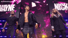 a group of people are standing on a stage in front of a purple background .