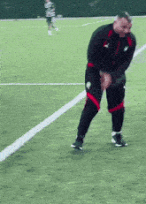 a man in a black jacket and red shorts is standing on a soccer field