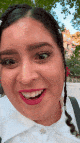 a woman with braids and pink lipstick is smiling