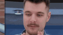 a close up of a man 's face with a blue shirt on