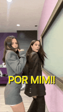 two women are dancing in front of a pink wall with the words por mim written above them