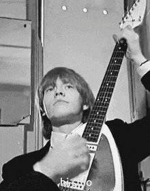 a man in a suit is holding a guitar in his hands .