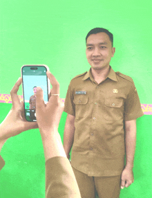 a man in a tan uniform is being photographed by someone with a cell phone