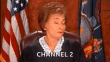 a judge is sitting in front of an american flag in a courtroom and says channel 2 .