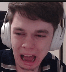 a young man wearing headphones is making a funny face with his mouth open .