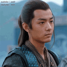 a man with long hair and a ponytail looks to his right