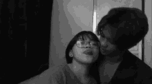 a black and white photo of a man and a woman kissing .