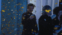 a group of people standing in a room with confetti falling on them