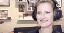 a woman wearing headphones is sitting on a couch and smiling .