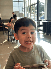 a young boy is holding a cell phone in his hands and making a funny face