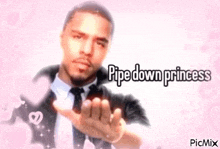 a man in a suit and tie is blowing a kiss with a pink background .