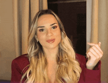 a woman in a red blazer is making a heart shape with her hand