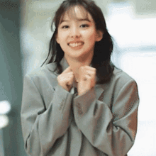 a woman in a suit is smiling with her hands folded .