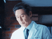 a man in a white coat and tie has the letters tm on his chest