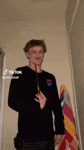a man in a black shirt is holding a wand and has a tiktok sticker on his face