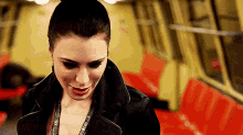 a woman in a black leather jacket is smiling on a subway train .