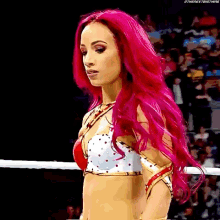 a woman with bright pink hair is standing in a ring .