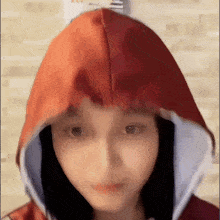 a woman wearing a red and white hoodie is making a face .