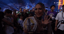 a woman holding a wrestling championship belt in front of a crowd .