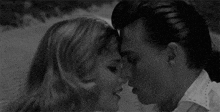a man and a woman are kissing each other in a black and white photo .